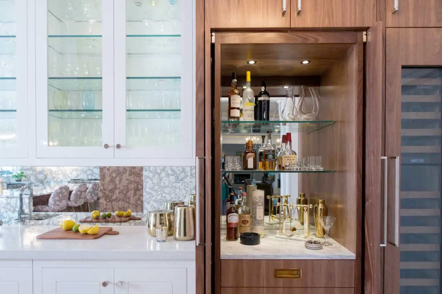 Photo of part of a kitchen. On the left are white cabinets and a counter. On the right are brown cabinets with a built-in beverage center and wine rack.