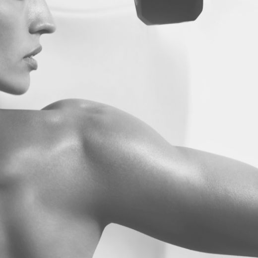 Womans face in profile with arm and shoulder muscle flexed with a hint of a barbell