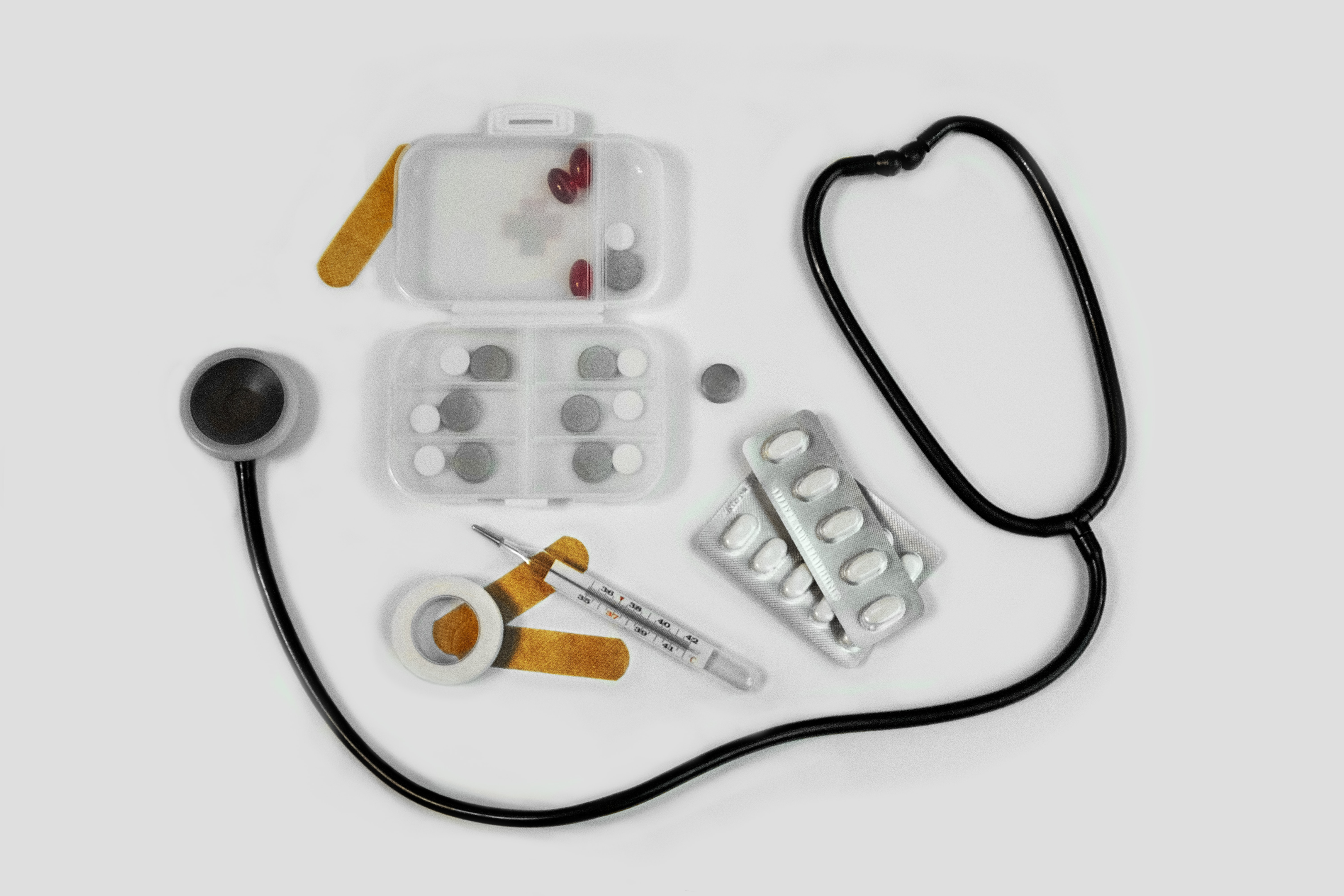 A top view of a stethoscope with medicines, bandages, and a thermometer kept together.