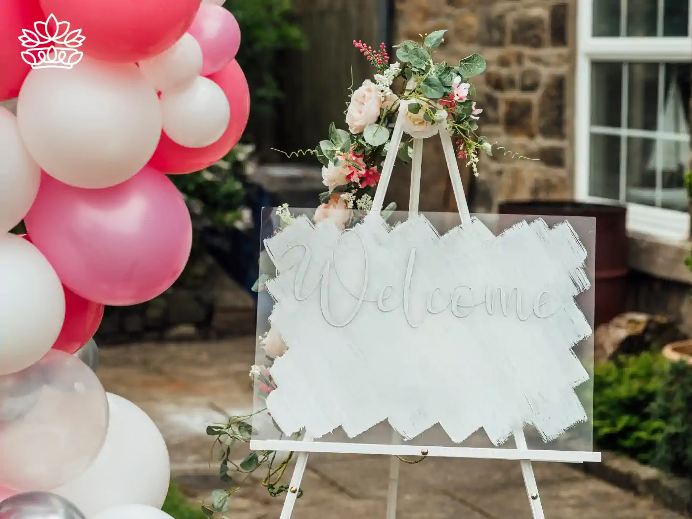 Welcome sign adorned with pink and white balloons and floral decorations, inviting guests to a baby shower celebration. Fabulous Flowers and Gifts: Baby Shower Flowers Collection