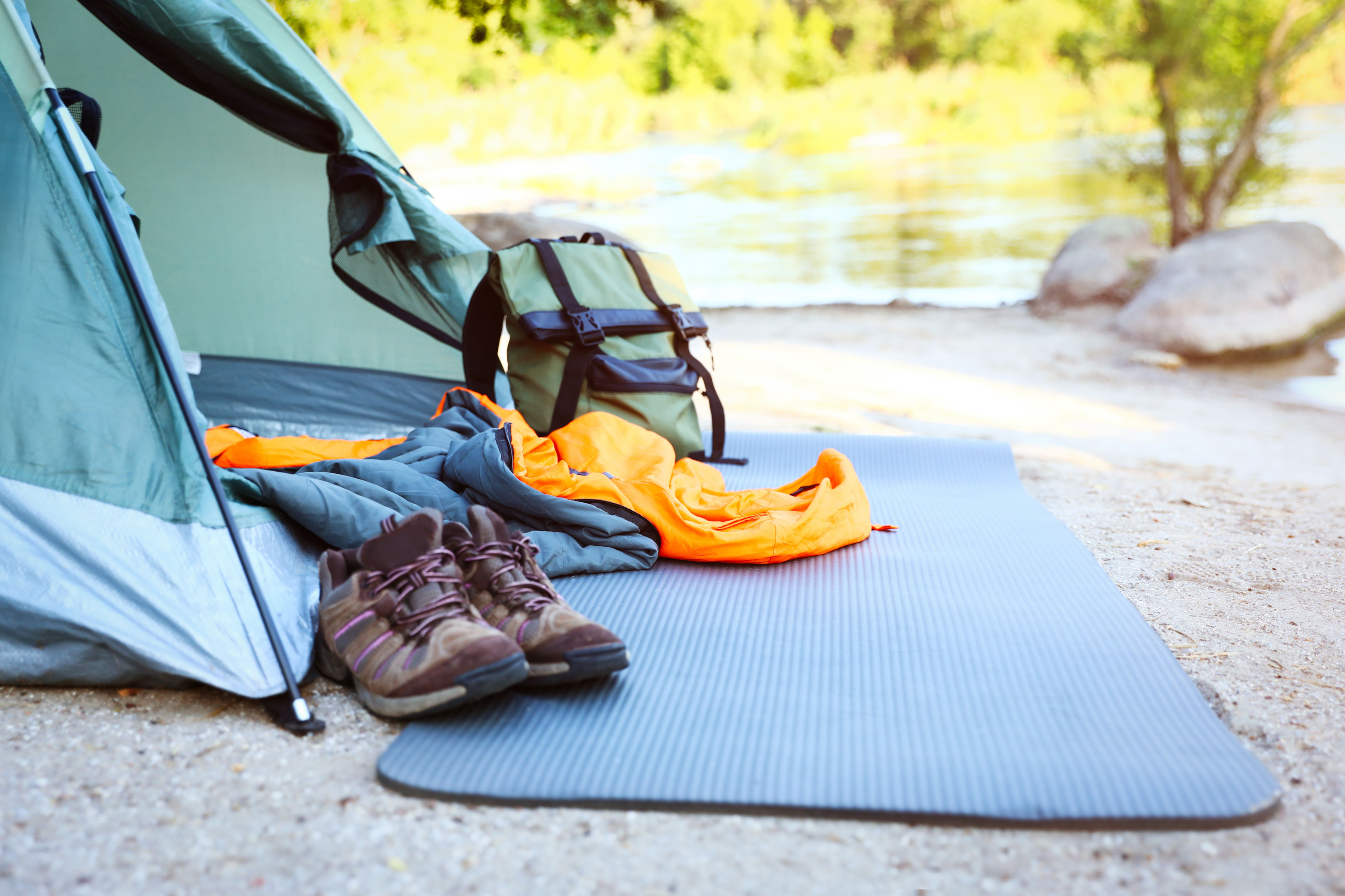 Outdoor and camping gears placed on a yoga mat and a portable camp is installed near