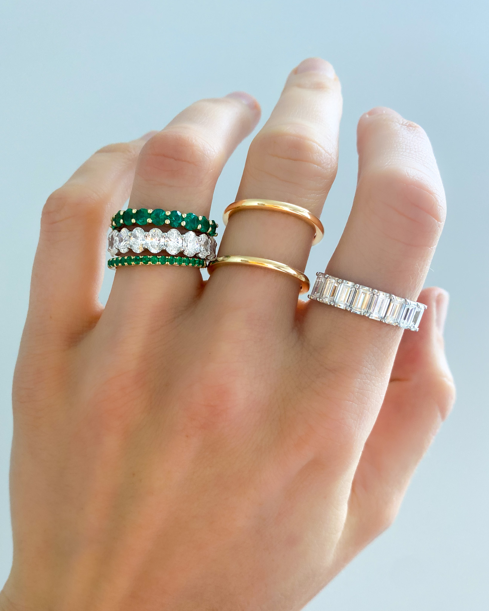 An Oval diamond eternity band paired with emerald stackable wedding bands