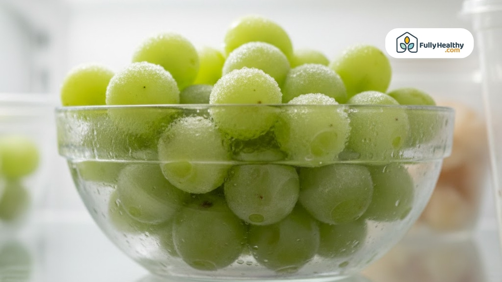 Frozen green grapes in glass bowl with visible frost and condensation