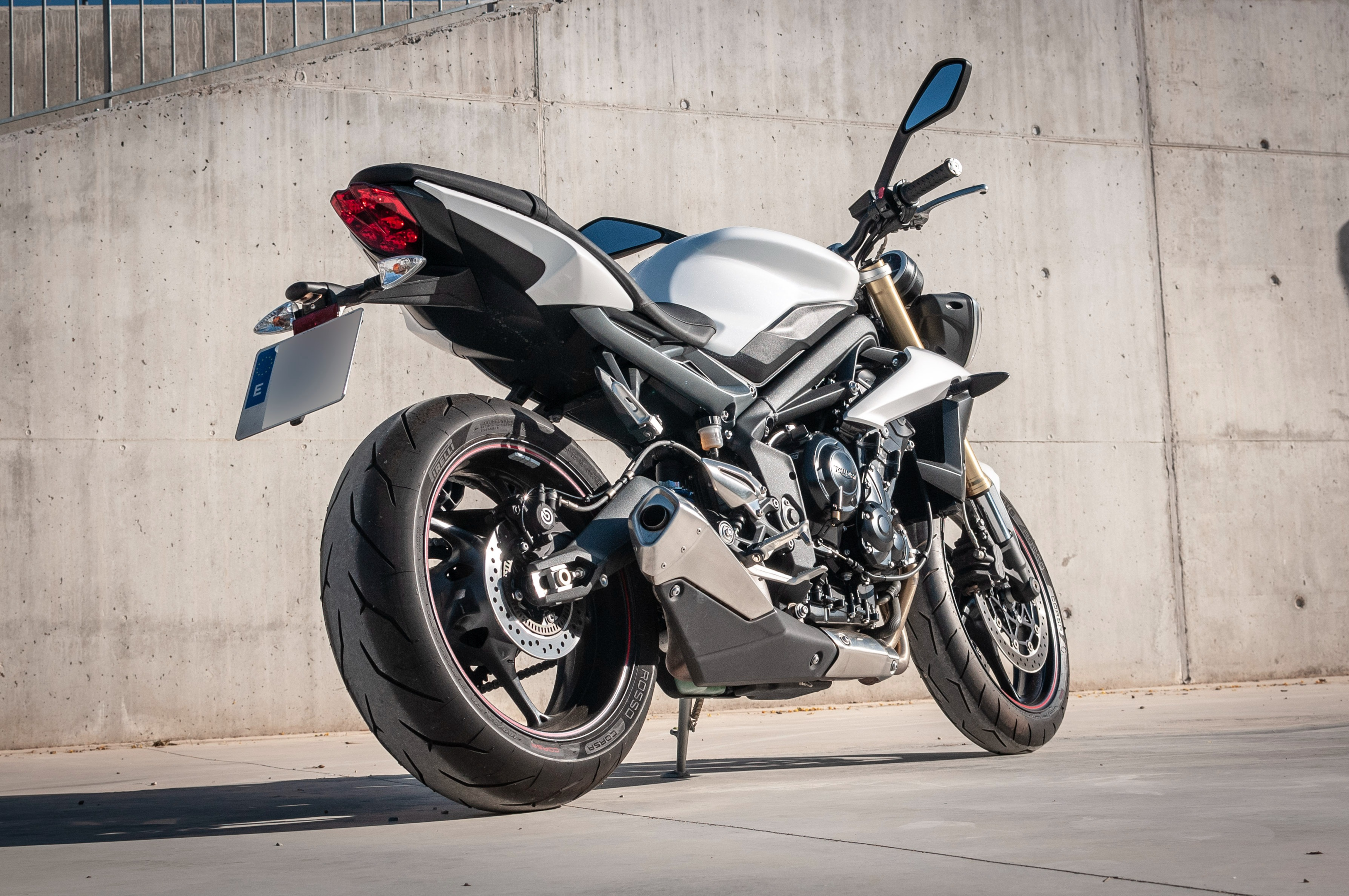 Black and Gray Naked Sports Bike Parked Besides Gray Concrete Wall ·