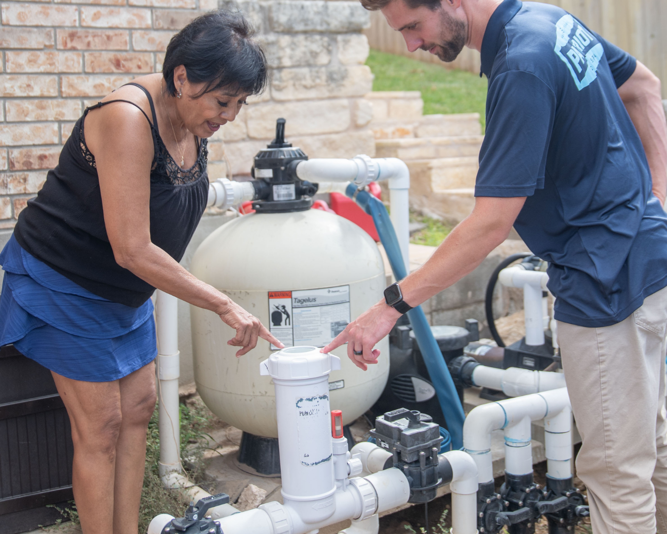 A pool technician pointing to an issue on the pool equipment pad.