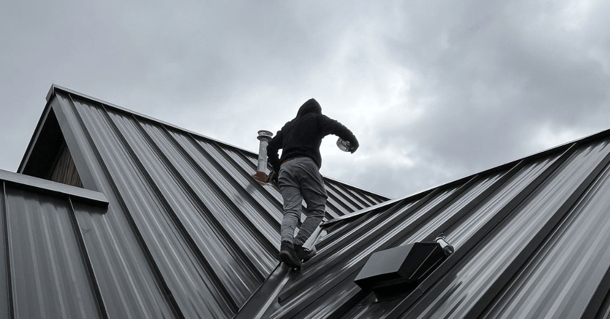 Roofer walking on a metal roof to conduct an inspection, highlighting the strength and durability of modern metal roofing.