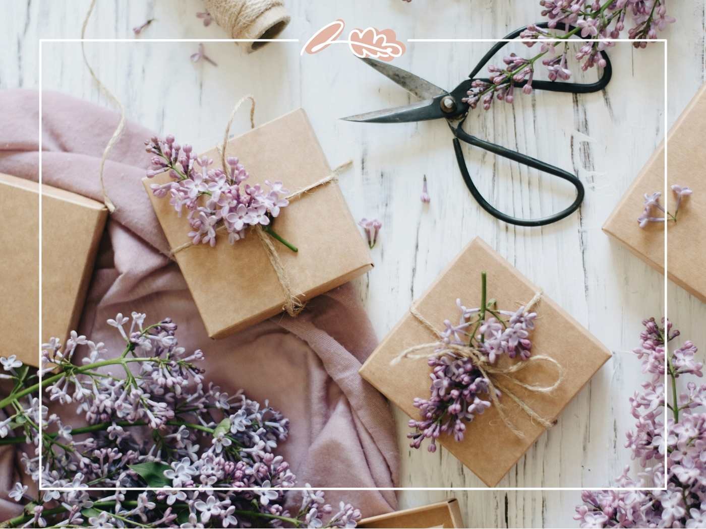 Gift boxes wrapped with twine and lilac flowers, with scissors nearby.