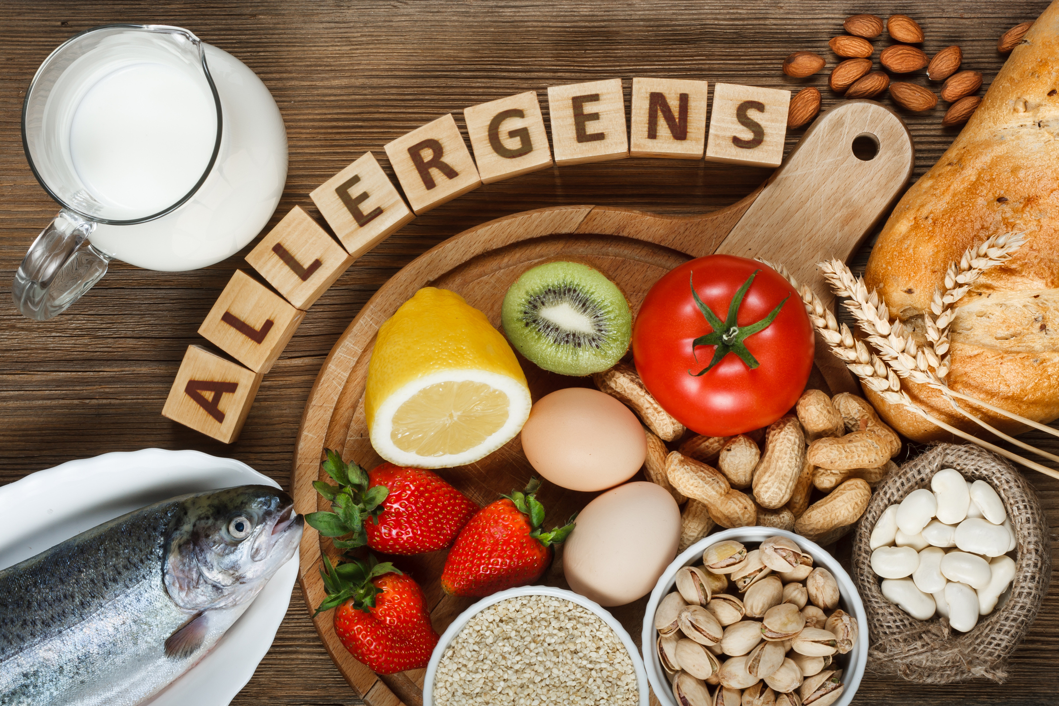 An image of various allergen foods, including peanuts, lima bean, eggs, wheat, milk, and strawberries with a sign that reads allergens.