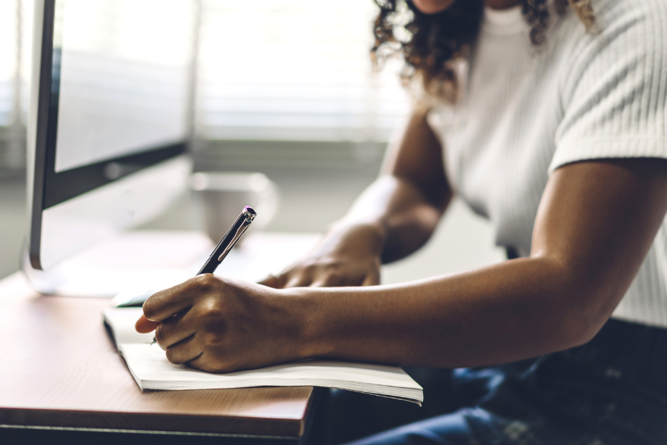 woman takes notes while reviewing an seo content audit on her computer