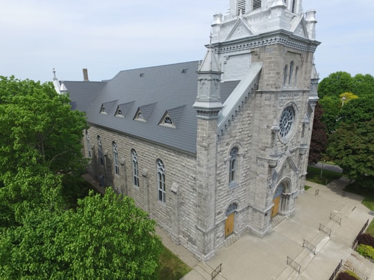 A cathedral roof, showcasing a tall, steep pitch, surrounded by greenery and installed by Roof Pros Plus.
