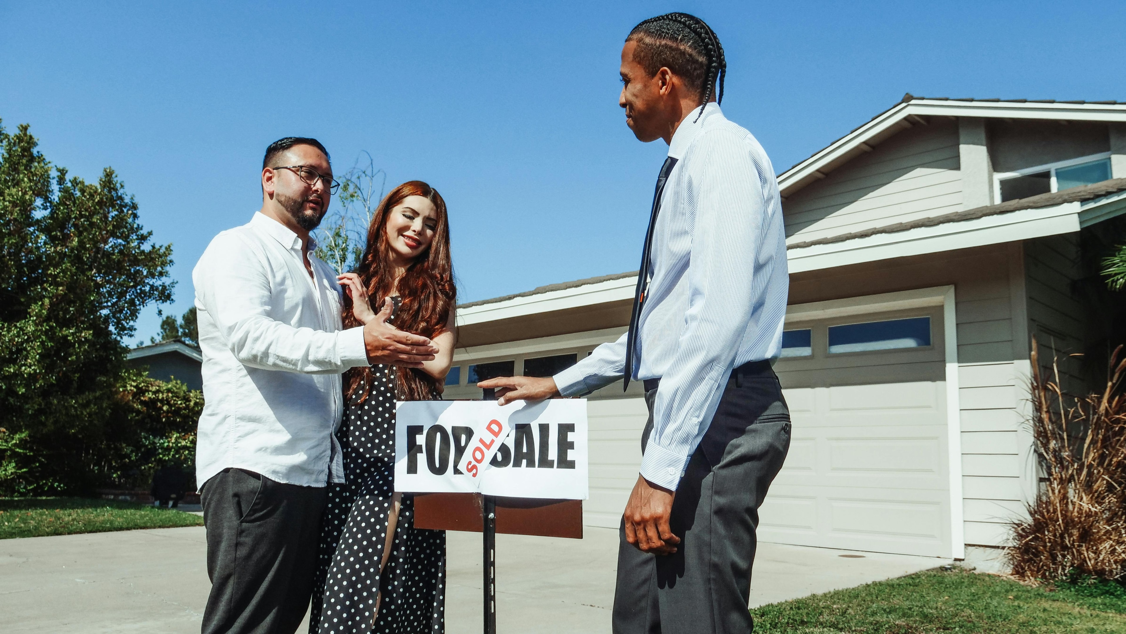 Real estate investor and inherited home heirs near home sold sign in front of property after closing.