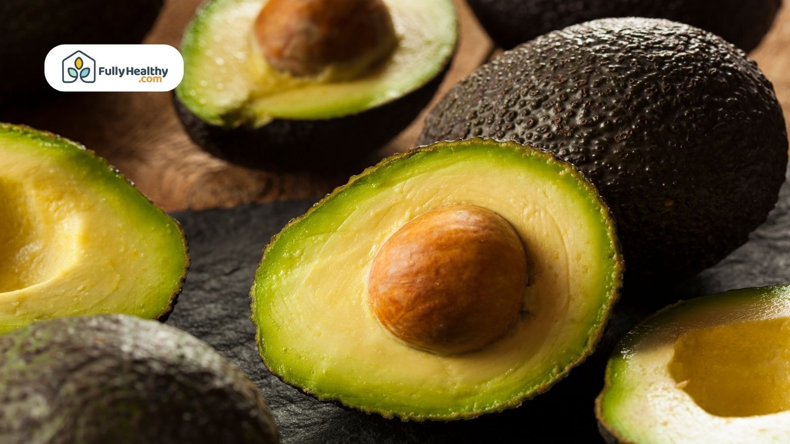 Halved ripe avocados on dark surface with visible creamy flesh
