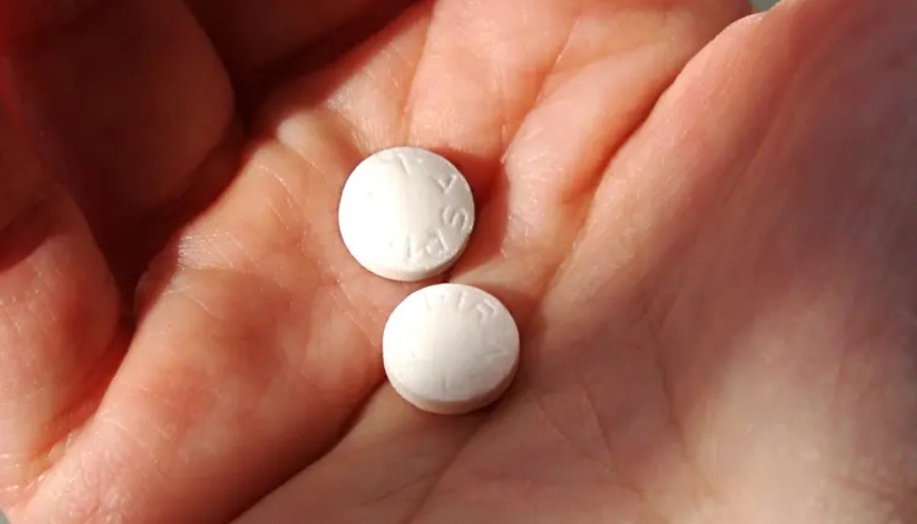To hvite tabletter i en åpen hånd, illustrasjon på medisinsk forsiktighet ved bruk av smertestillende.
