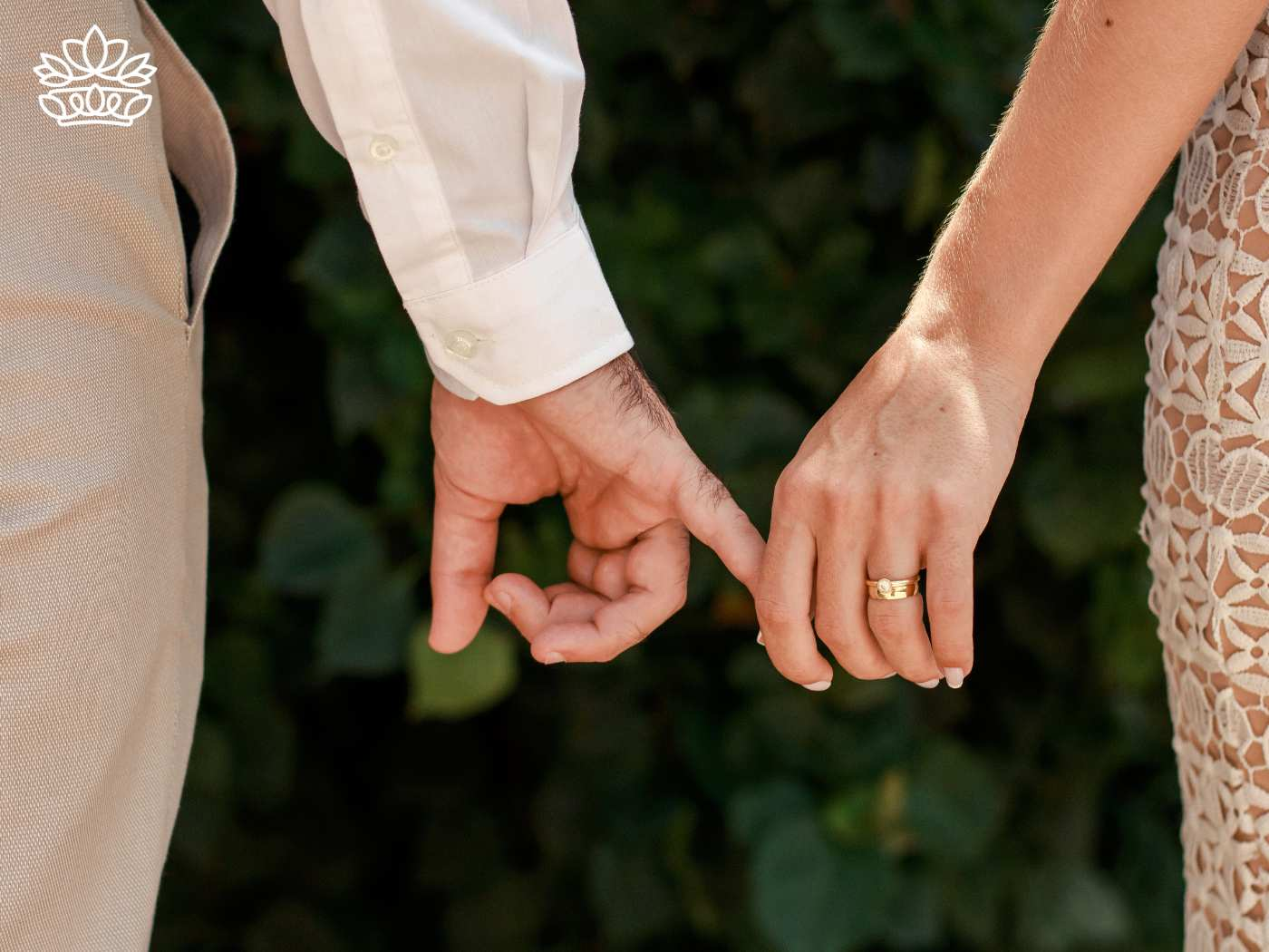 Close-up of a couple tenderly holding pinky fingers, showcasing their wedding rings against a backdrop of lush greenery. The intimate gesture highlights their connection and commitment, perfect for celebrating with Fabulous Flowers and Gifts. Gift Boxes for wife. Delivered with Heart.