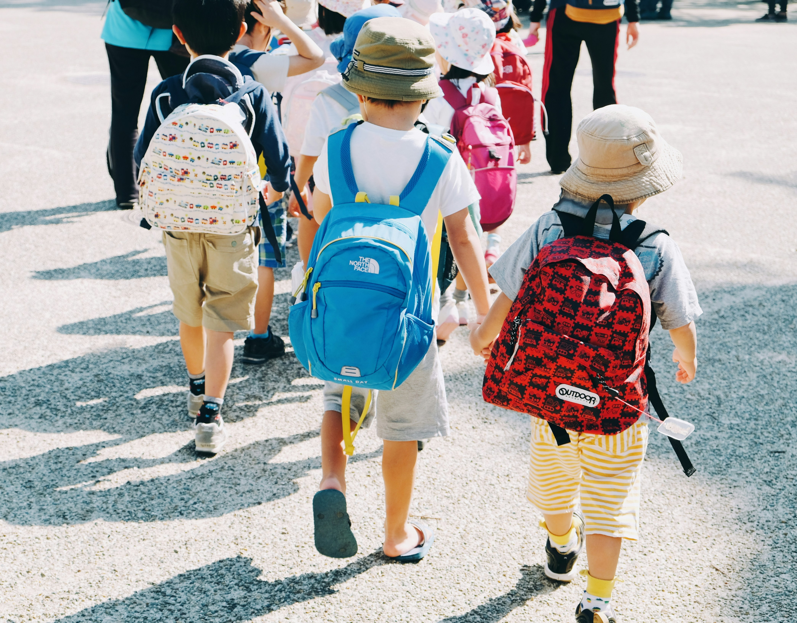 Multiple kids walking carrying their bags over their shoulders