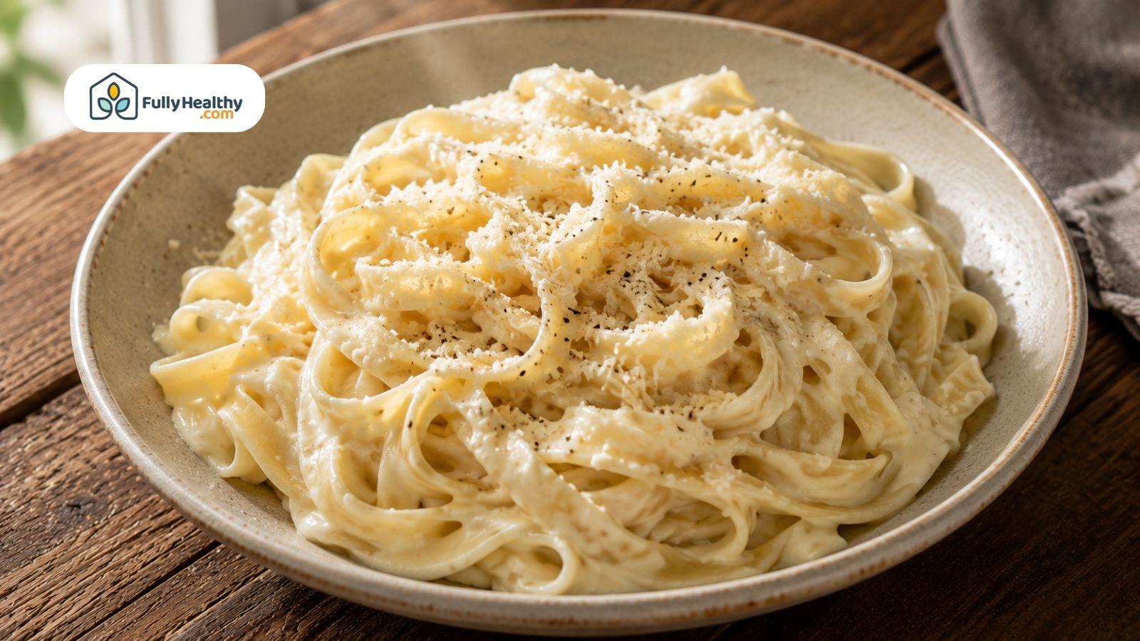 Creamy fettuccine pasta topped with grated Parmesan cheese served in ceramic bowl.