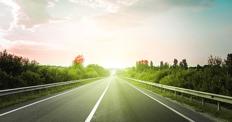 Road stretching toward a sunrise horizon, symbolizing AI guardrails as guidance and refinement rather than unchecked expansion.