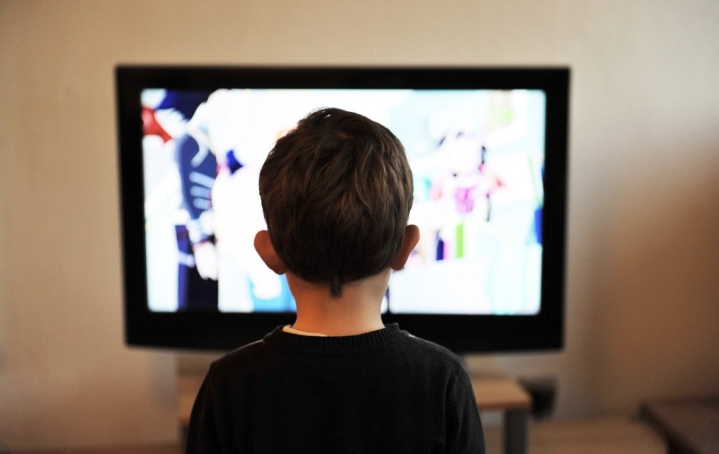 A child watching television in a dimly lit room