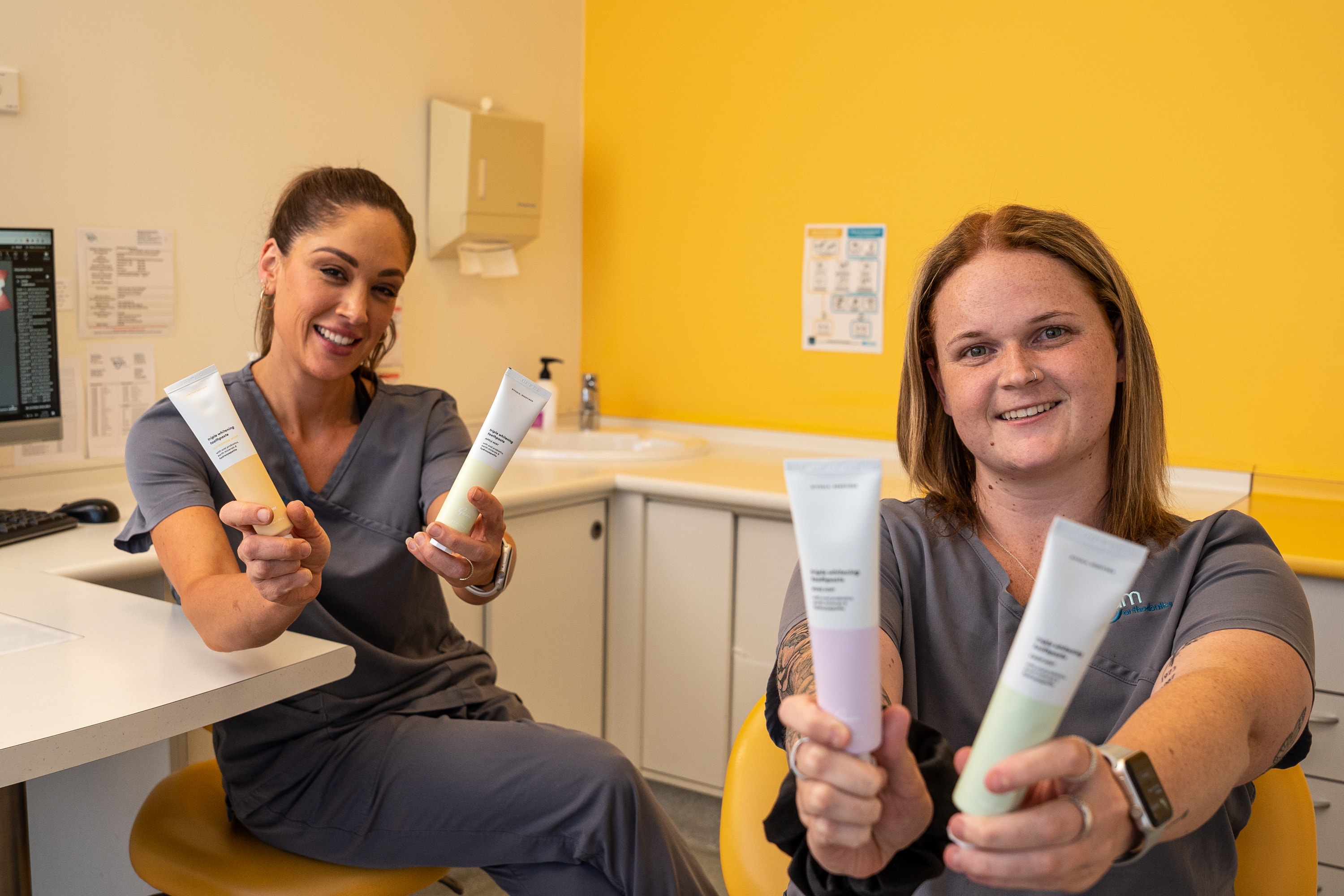 Two dental professionals showing off Gem Kind toothpastes