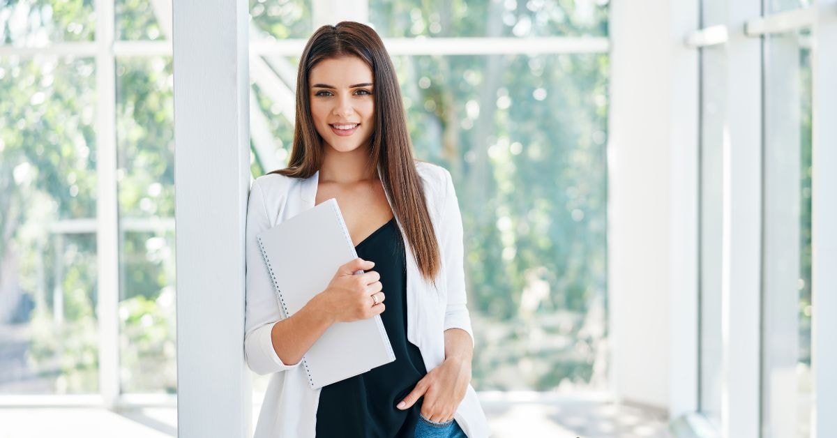 Smiling woman with fidelity tax documents standing in a sunny office environment.