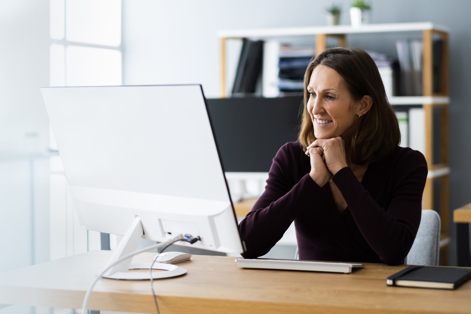 A manager smiling while talking to an employee during a virtual meeting.