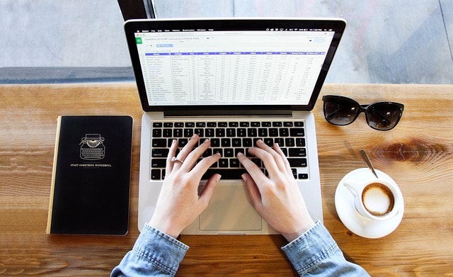 hands typing into a spreadsheet on a laptop