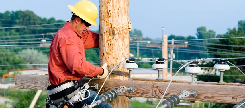 Utility worker climbing utility pole. Credit: Canva