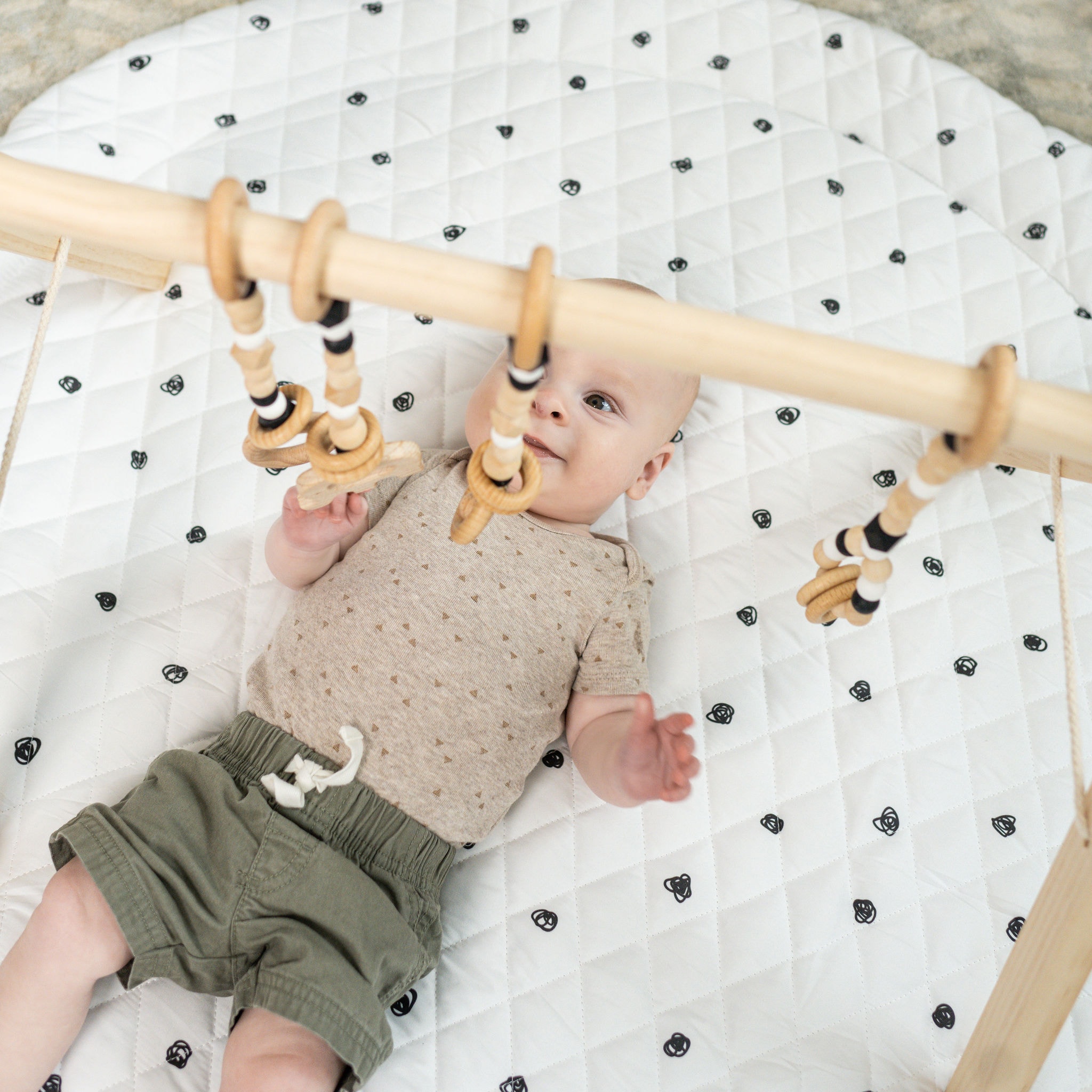 Baby playing with play gym by Poppyseed Play