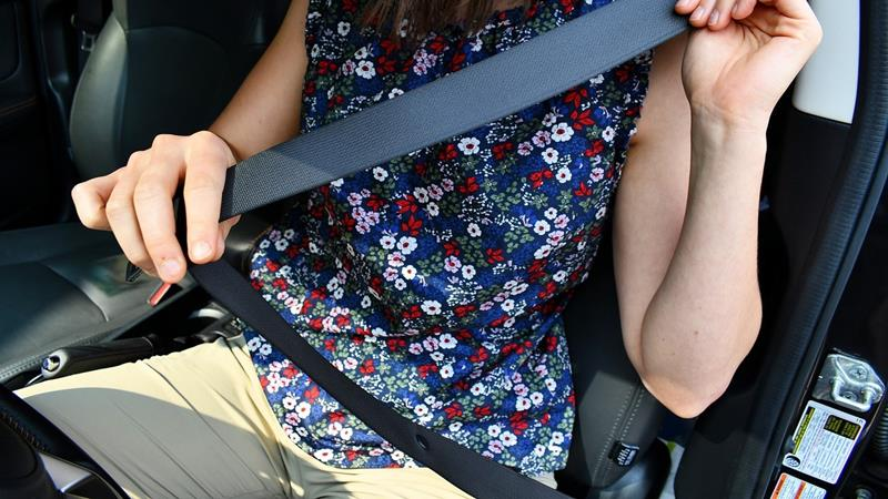 Woman putting on seatbelt in car.