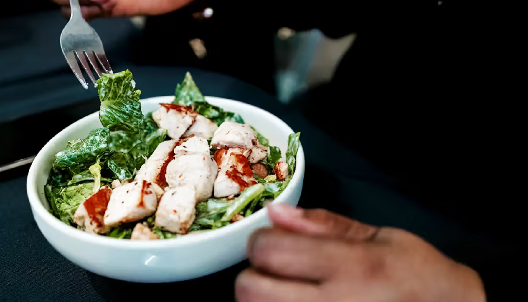 "En bolle med frisk salat toppet med grillede kyllingbiter, klar til å spises."