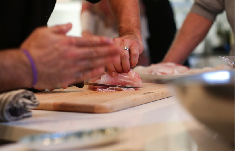 Group of people learning knife skills in a cooking class in Austin