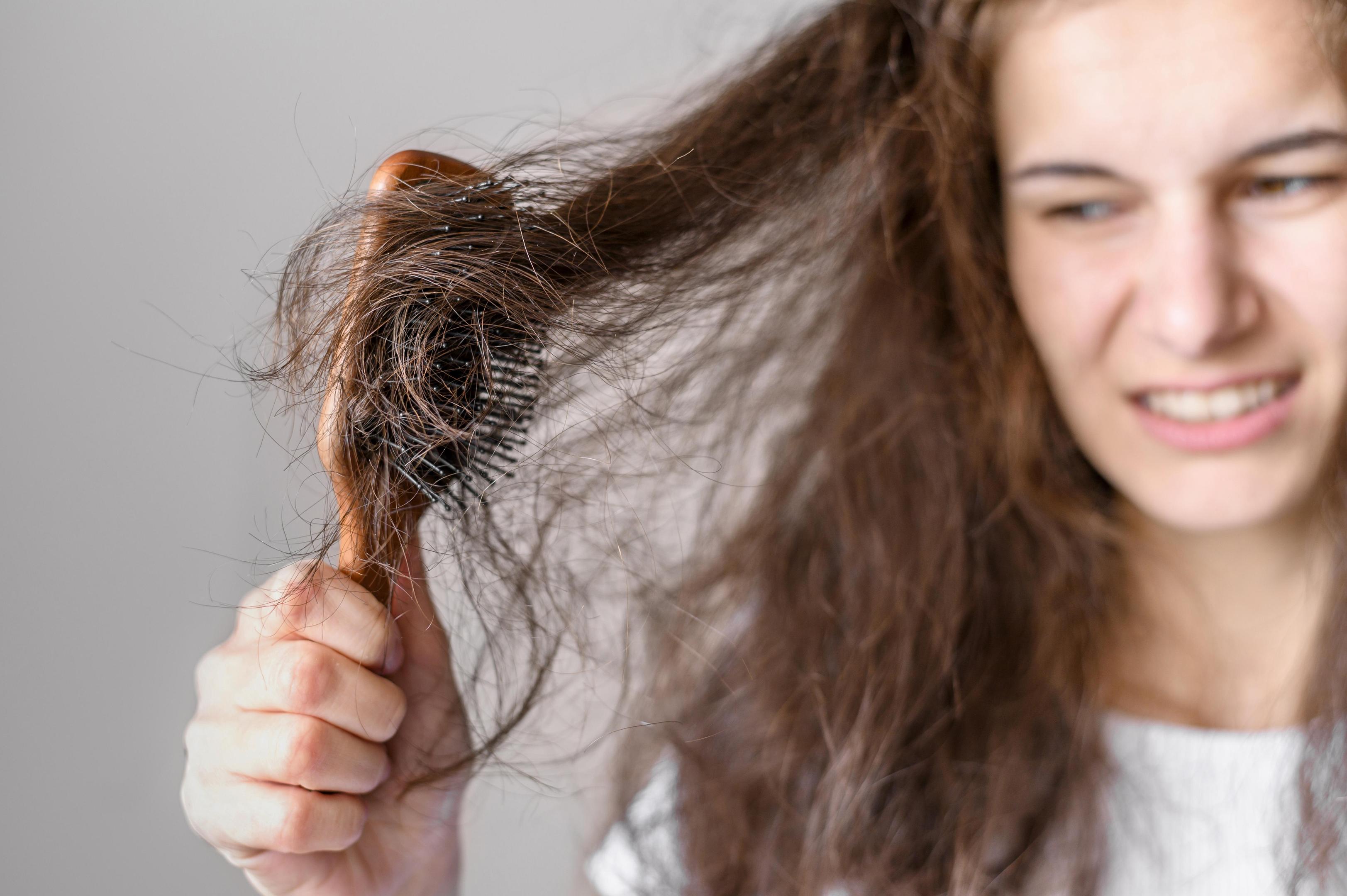 a woman combing her dry, damaged hair
