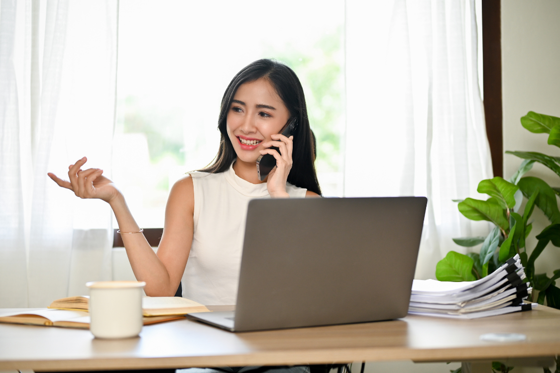 Young Filipino woman working remotely while speaking on the phone