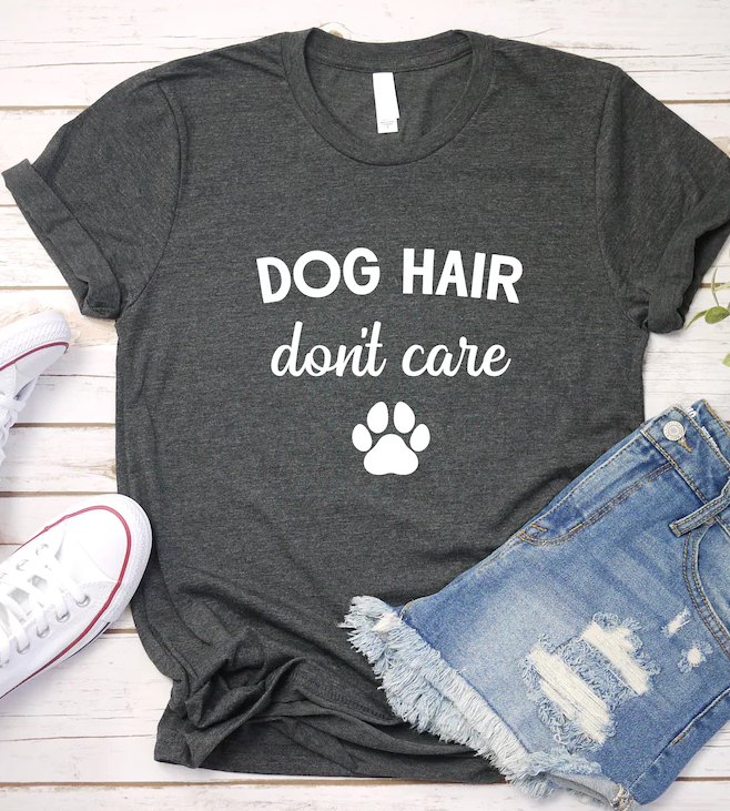 Tshirt with text Dog Hair Don't Care and a Paw Print. Sneakers and shorts near t-shirt.