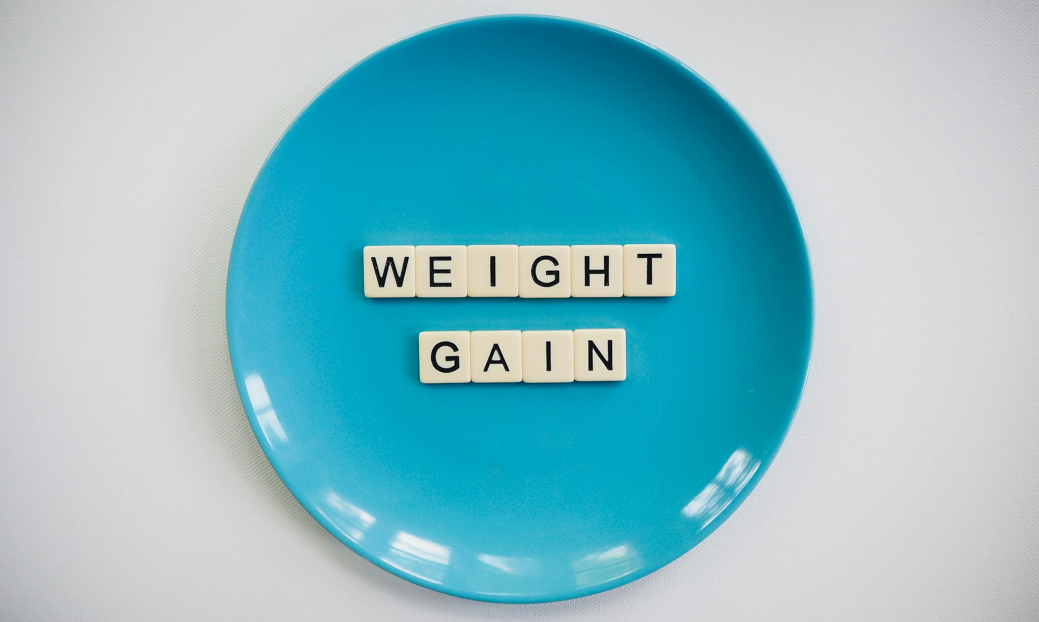 An illustration showing the connection between hormonal imbalance and weight gain, featuring a scale and various food items.