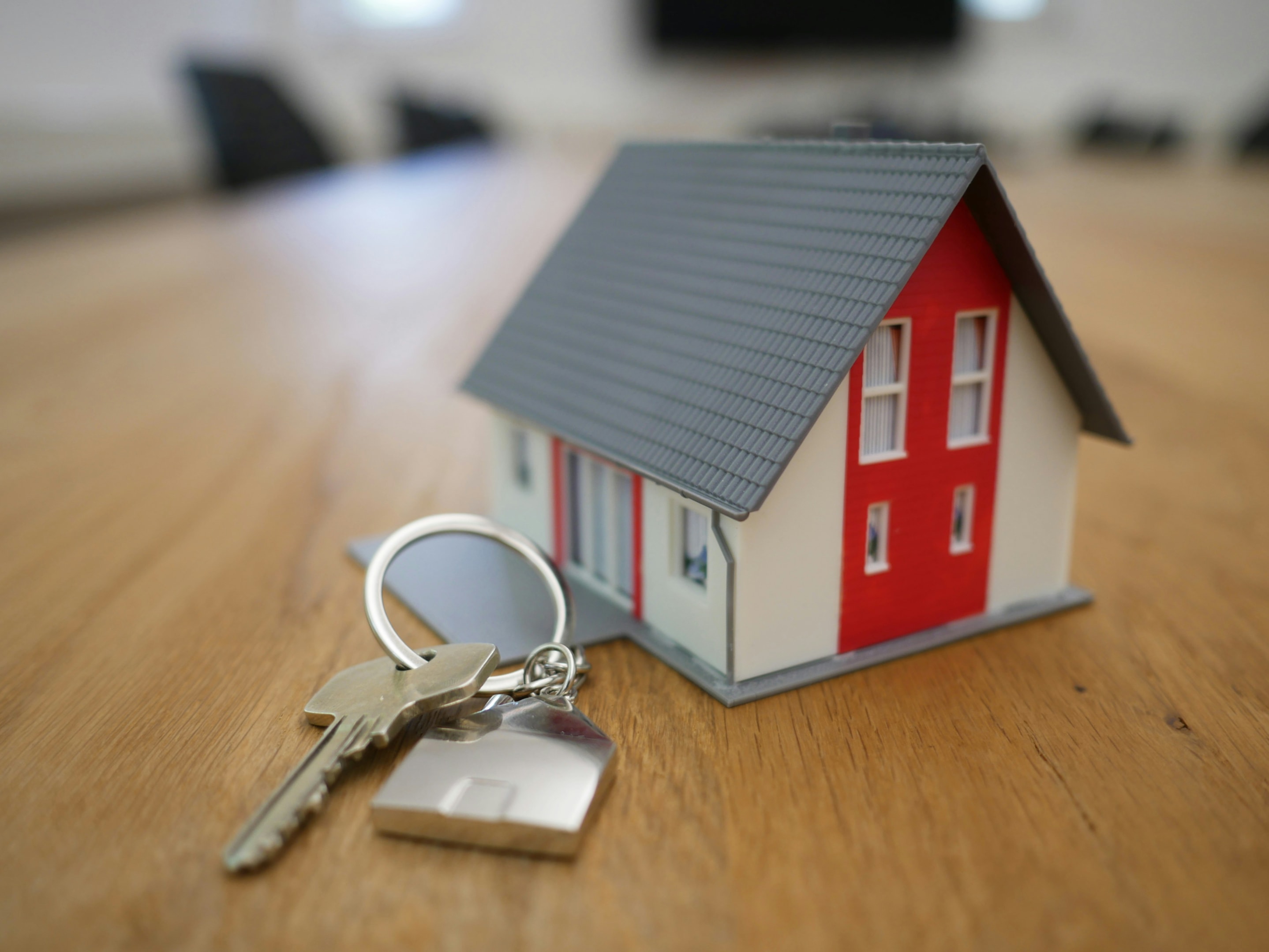 House keys alongside small model of home that will be passed to real estate investor after closing on a new property.