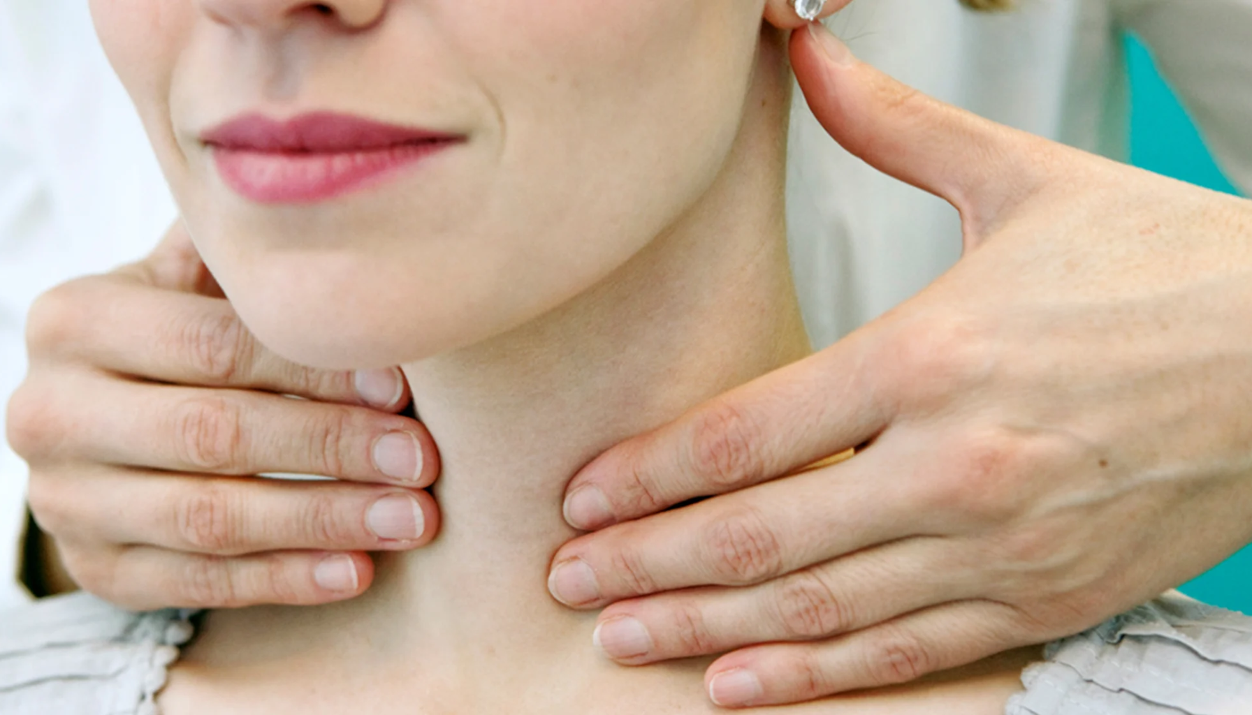 Lege undersøker skjoldbruskkjertelen på halsen under konsultasjon.