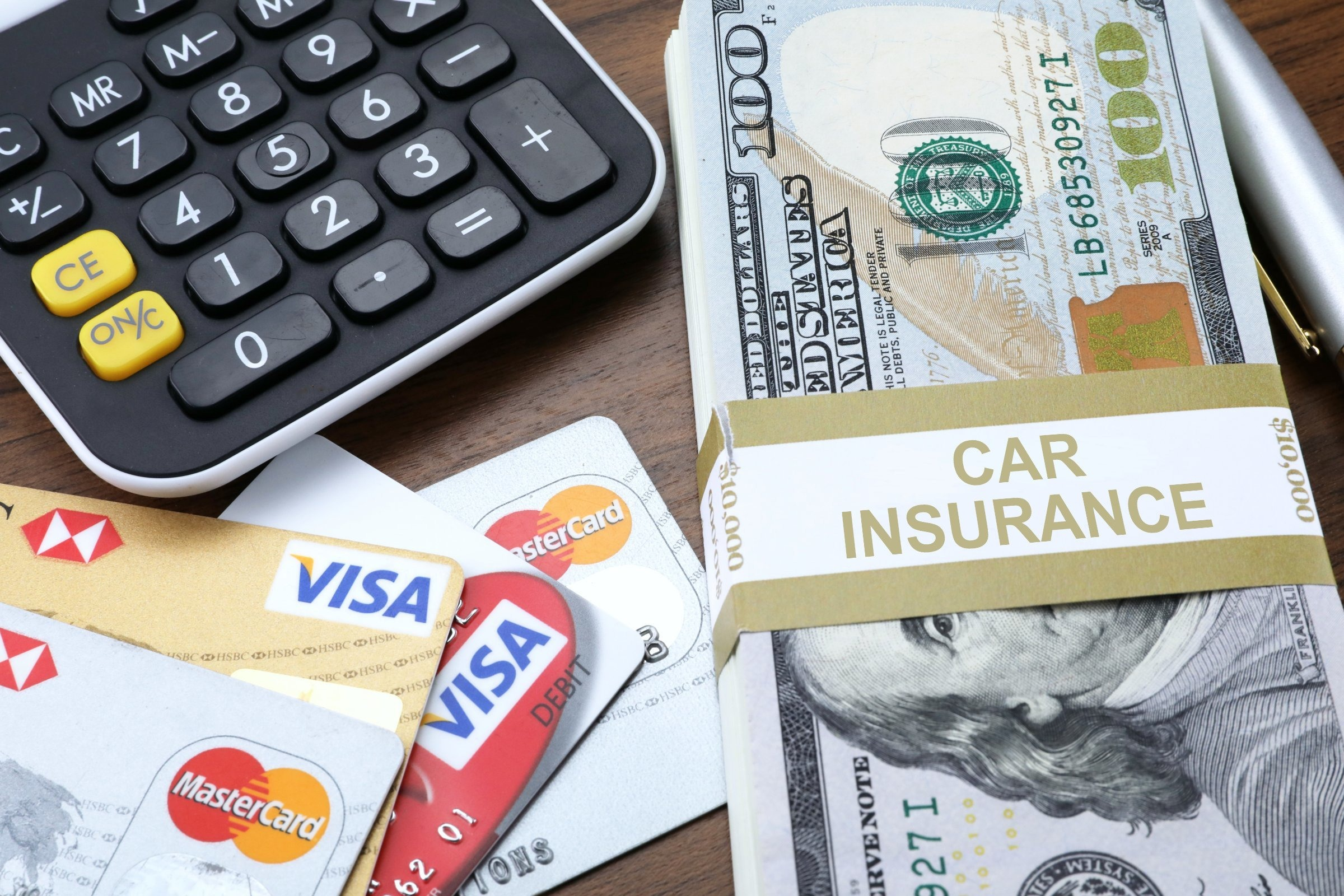 Calculator, credit card, and a bundle of money for car insurance