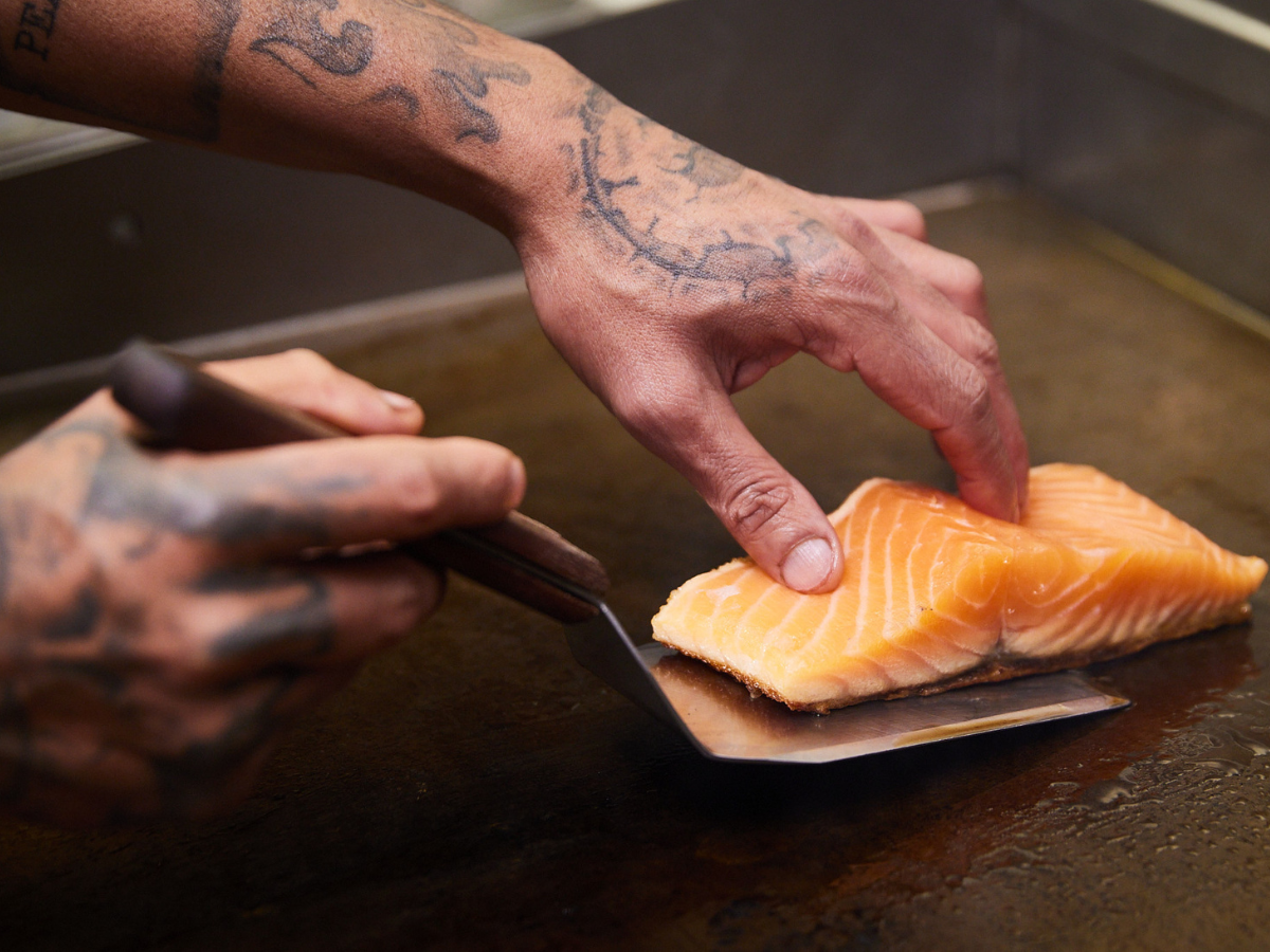 A Fitchies chef prepares sustainable seafood, a piece of delicious salmon is prepared by placing it on the grill