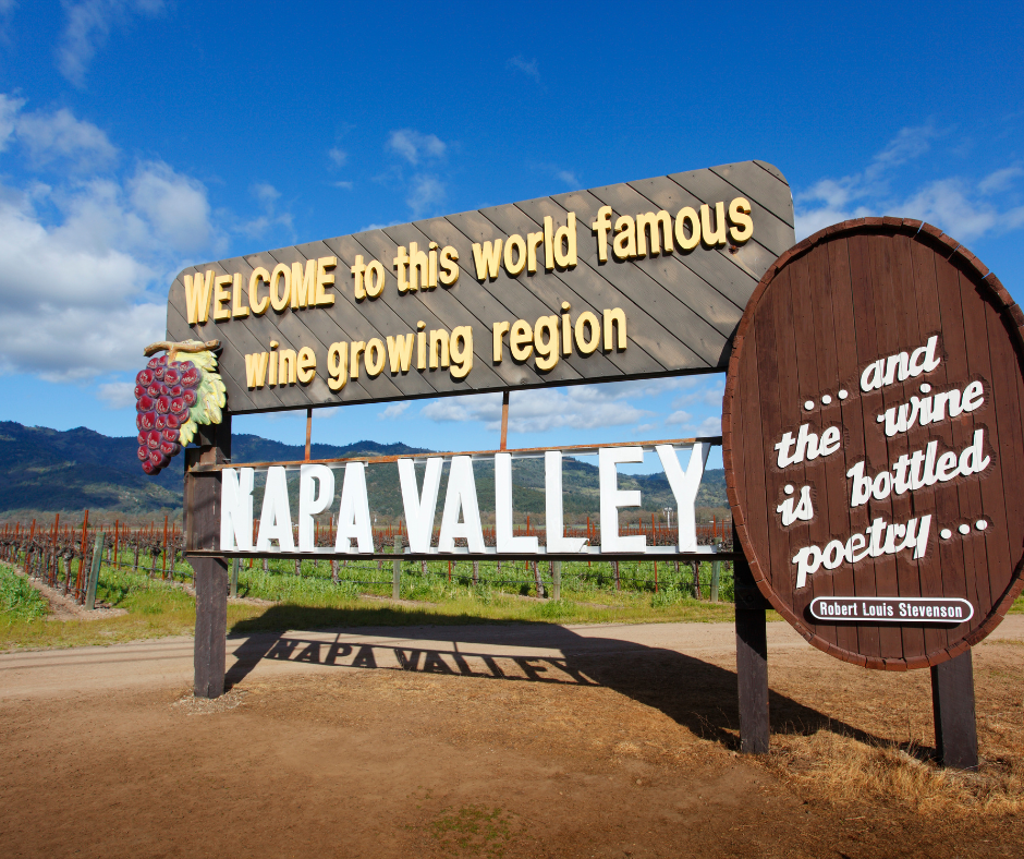 Napa Valley welcome sign with grape vines in the background. Napa is also home to olive and oak trees.