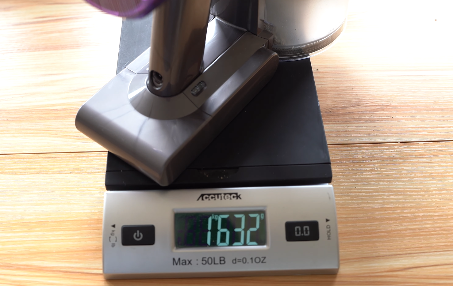 Dyson V8 vacuum being weighed after collecting sand from carpet