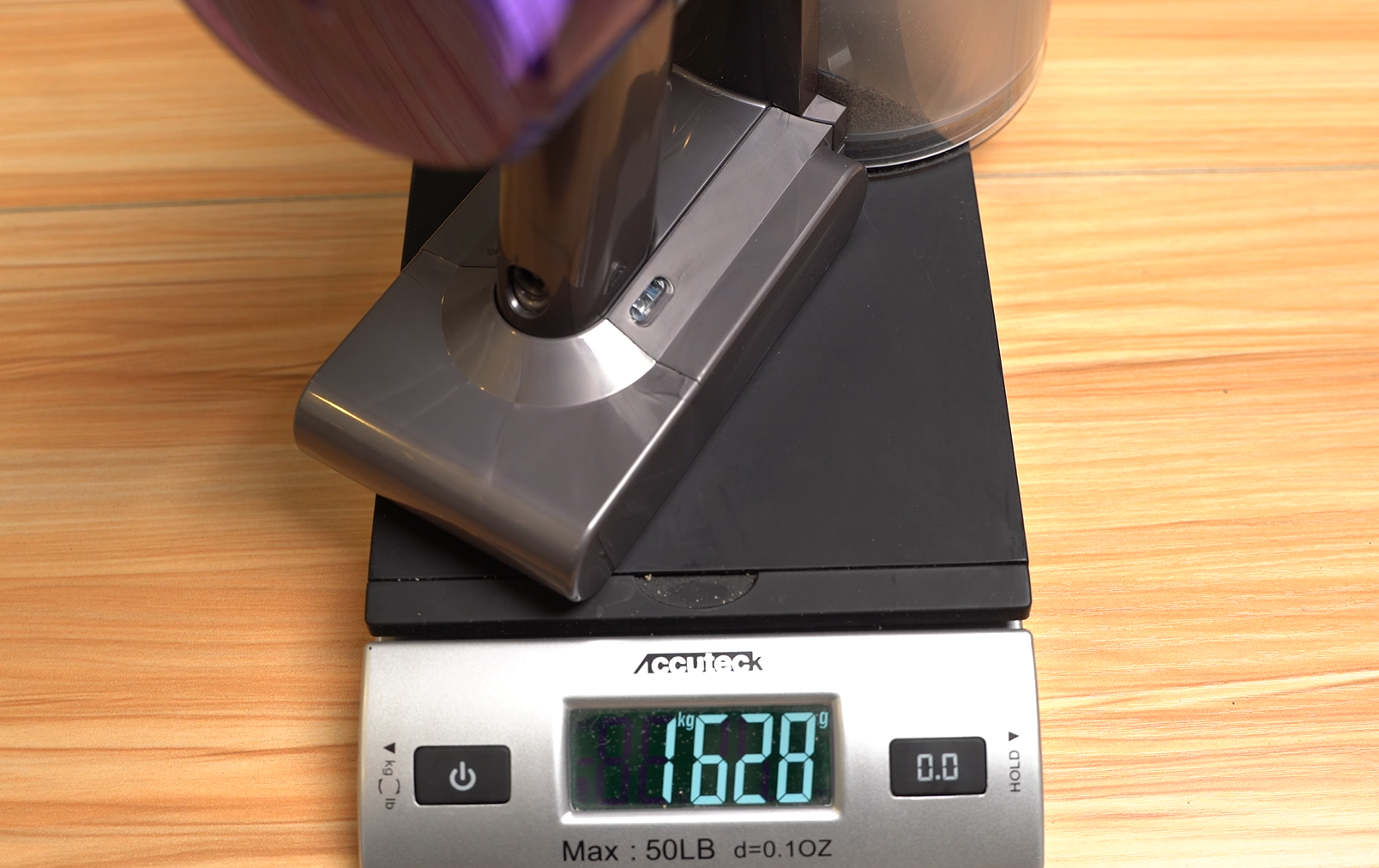 Dyson V8 vacuum being weighed after collecting sand from carpet