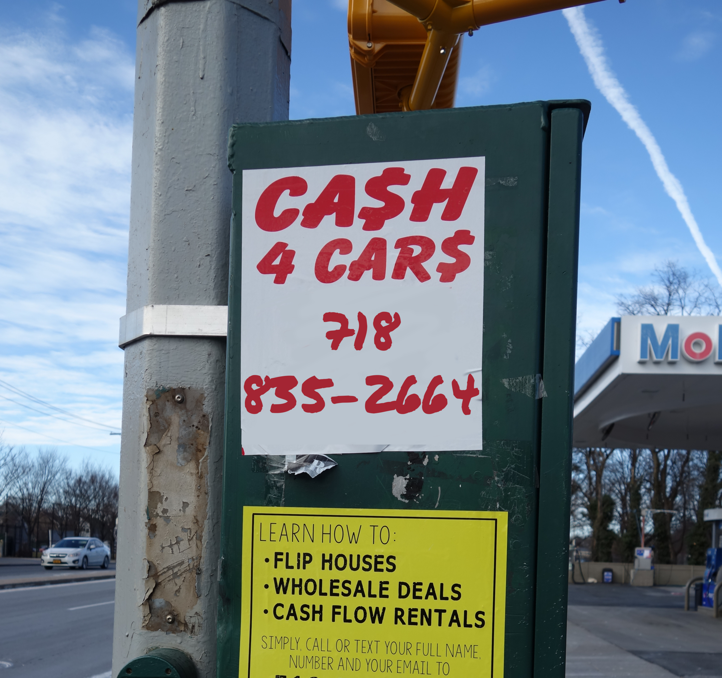 A man holding a sign with "Cash for Cars" written on it