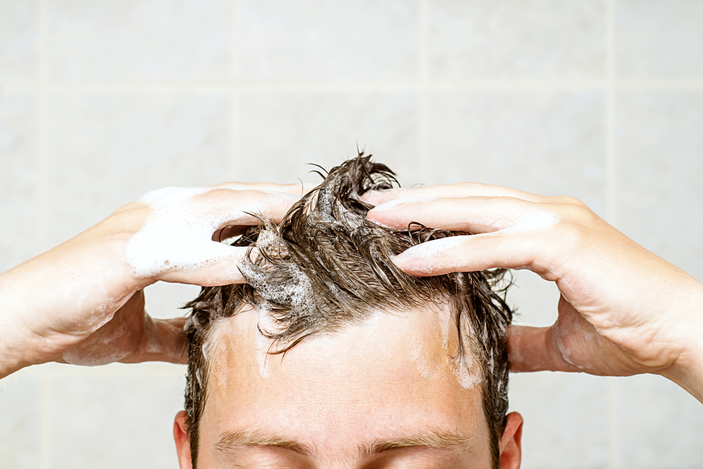 Man lathering his hair with shampoo in the shower