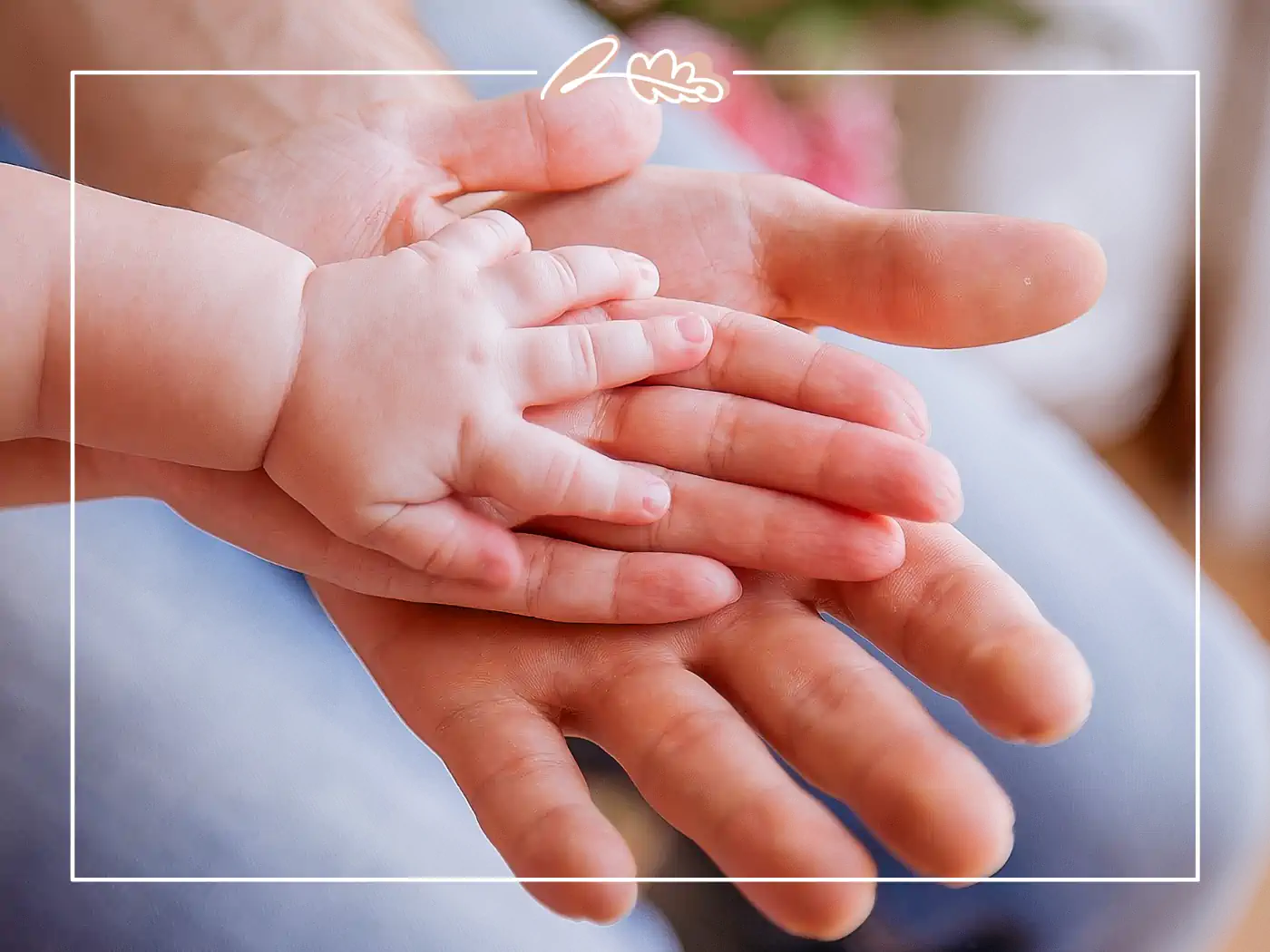 A baby's hand gently resting on an adult's hand, showcasing the bond of family. Fabulous Flowers and Gifts.