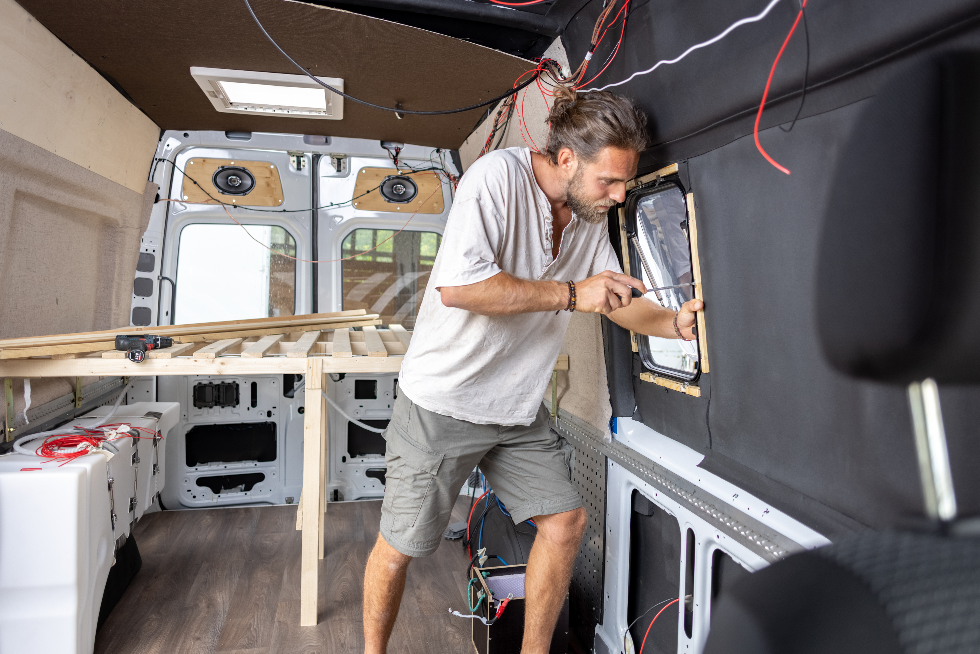 Mężczyzna instaluje okno w furgonetce na kemping