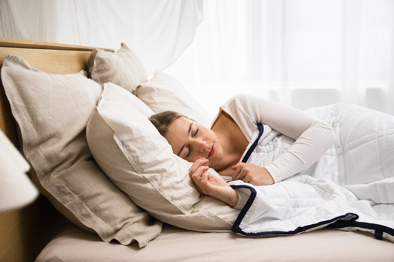 An image of a young woman napping in bed. 