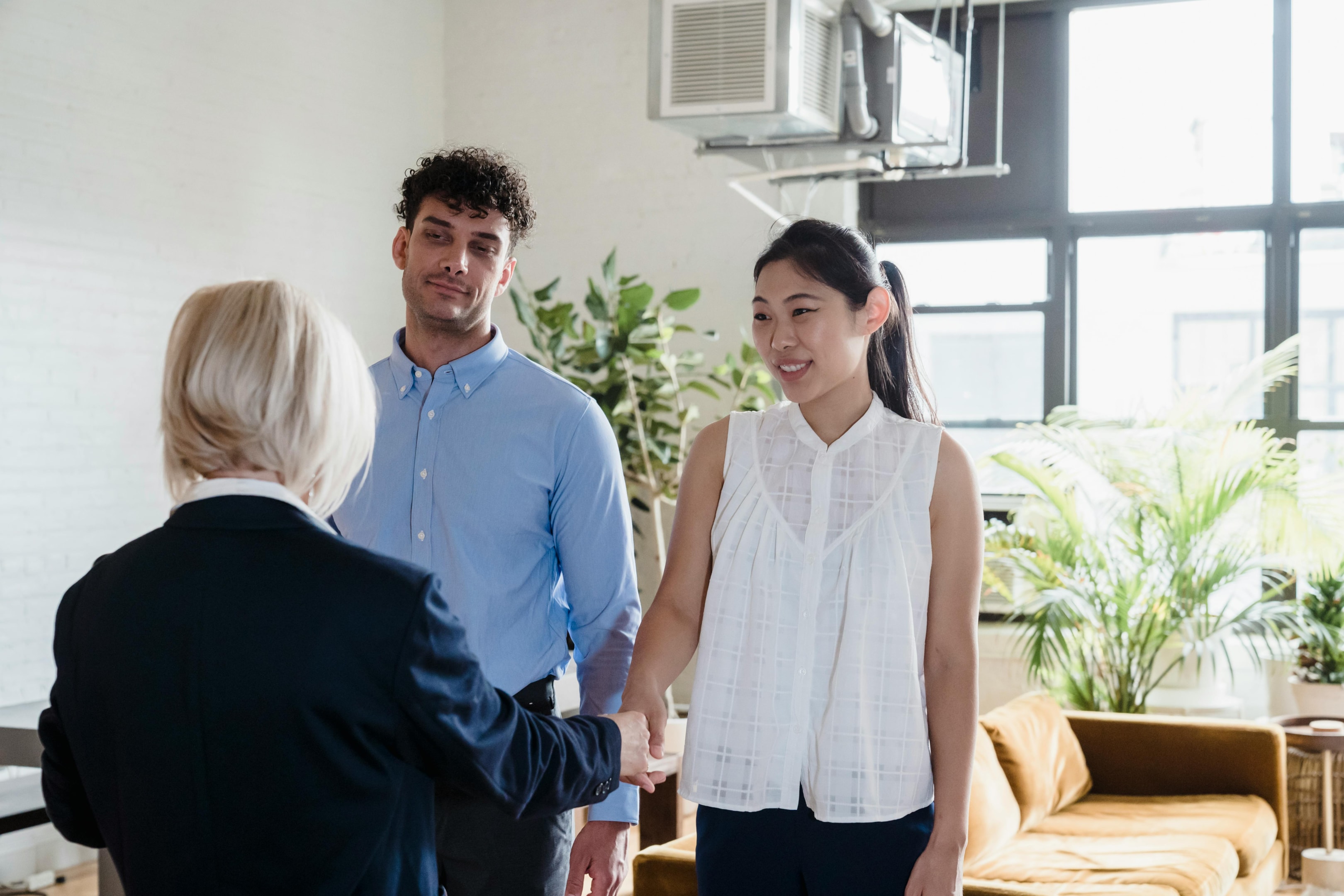 Real estate investor shakes hands of motivated sellers after closing on successful deal.