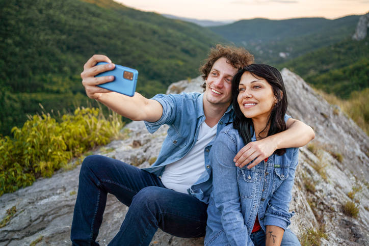 Sweet young couple hugging on top of a rock.