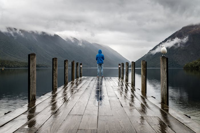 Person standing on wooden pier in the rain